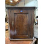 A 19th century oak hanging corner cupboard with three shaped shelves enclosed by a fielded panel