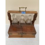 An oak triple decanter stand fitted with lidded compartments and drawer