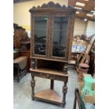 An oak carved standing corner display cupboard enclosed by a pair of glazed doors. 84' high