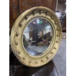 A 19th century convex looking glass, the parcel gilt frame with applied balls to the cavetto. 23'
