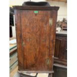 An early 18th century figured walnut hanging corner cupboard, the line inlaid door enclosing three