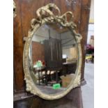 A 19th century gilt gesso oval looking glass, with ribbon-tie moulded frame. Plate later. 18½' high