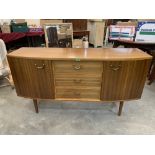 An early 1960s sideboard with a flight of three drawers and cupboards flanking, raised on tapered