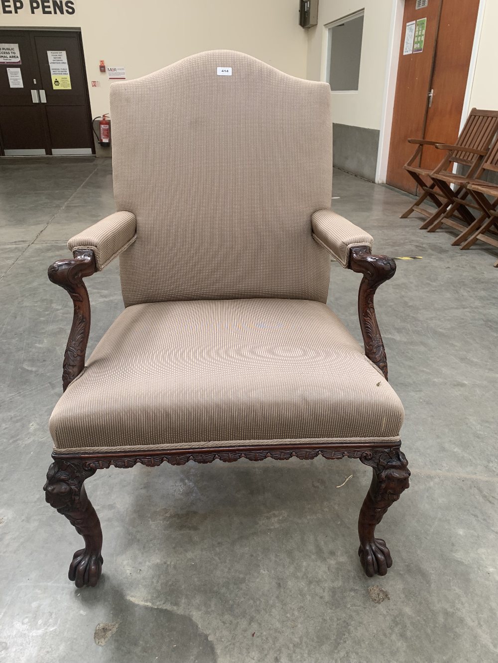 An antique mahogany Gainsborough elbow chair, carved with acanthus and foliage, raised on lion