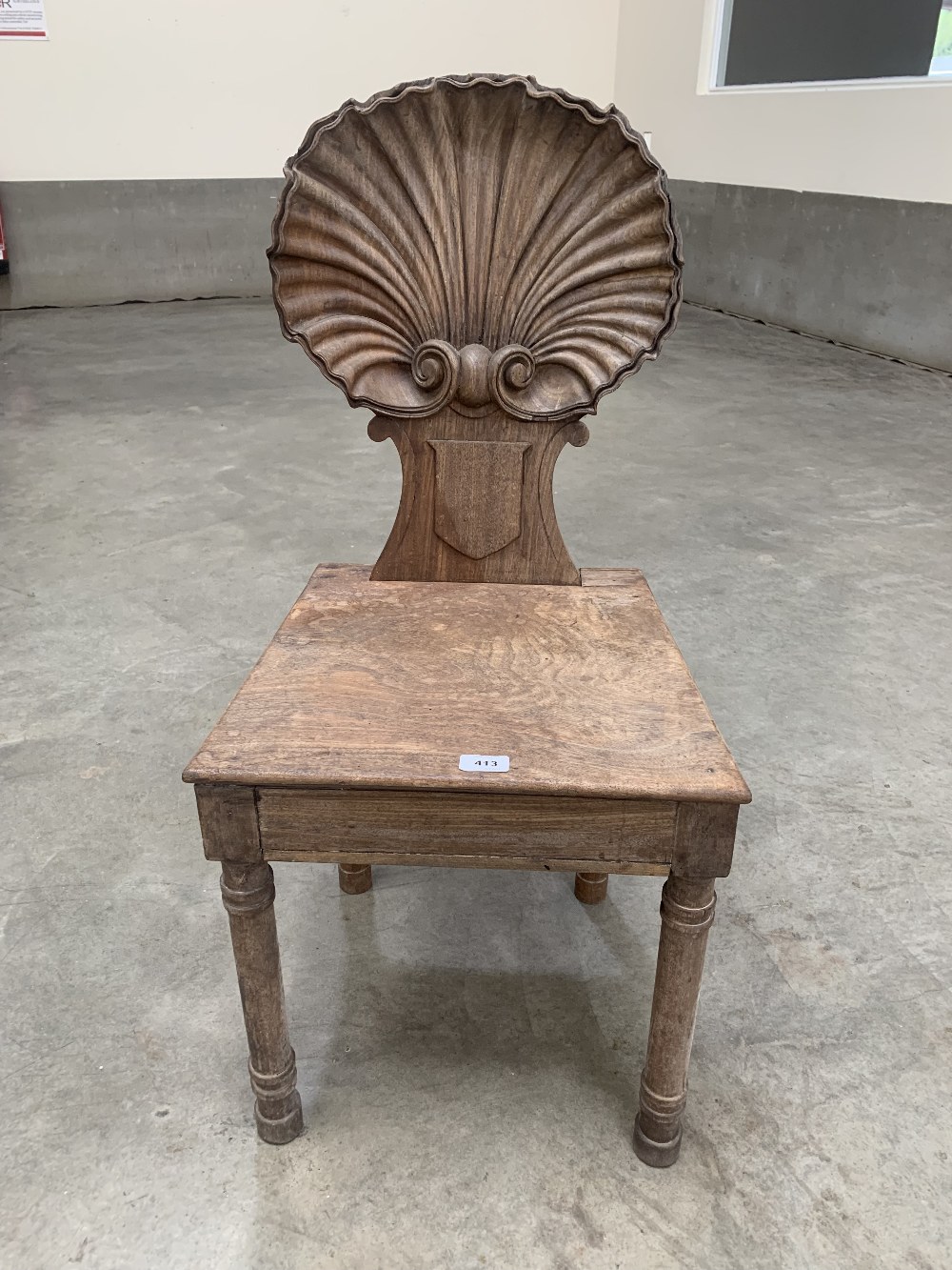 A 19th century mahogany hall chair, the back carved as a scallop shell, raised on ring turned legs