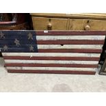 A stars and stripes painted wood panel. 23' x 48'