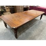 A late Victorian walnut dining table, raised on turned legs with brass caps and ceramic castors.