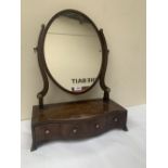 A George III mahogany dressing table mirror, the oval plate over serpentine base with three drawers,