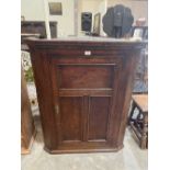 An 18th century oak corner cupboard enclosed by a triple panel door. 42½' high