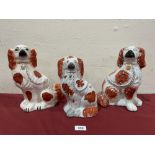 Three 19th century Staffordshire spaniels decorated in iron red. 9¼' - 11' high