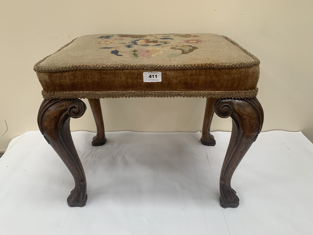 An antique walnut stool with foliate tapestry seat raised on scroll carved cabriole legs with hoof