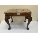 An antique walnut stool with foliate tapestry seat raised on scroll carved cabriole legs with hoof