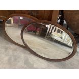 Two Edwardian mahogany oval wall mirrors with bevelled plates