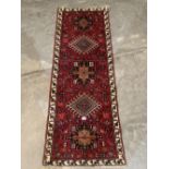 A Persian Karadja red ground carpet runner. 66' x 26'