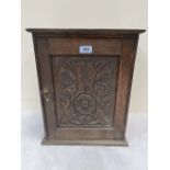 An oak carved wall cupboard, the panel door enclosing two drawers. 17' high