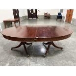 A Regency mahogany twin pedestal dining table with oval top, raised on ring turned pillars and