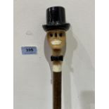 A hazel walking stick, the pommel carved as a grinning skull in top hat with glass eyes. 53' long