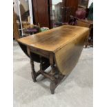 A joined oak gateleg dining table by Titchmarsh and Goodwin with frieze drawer, raised on turned