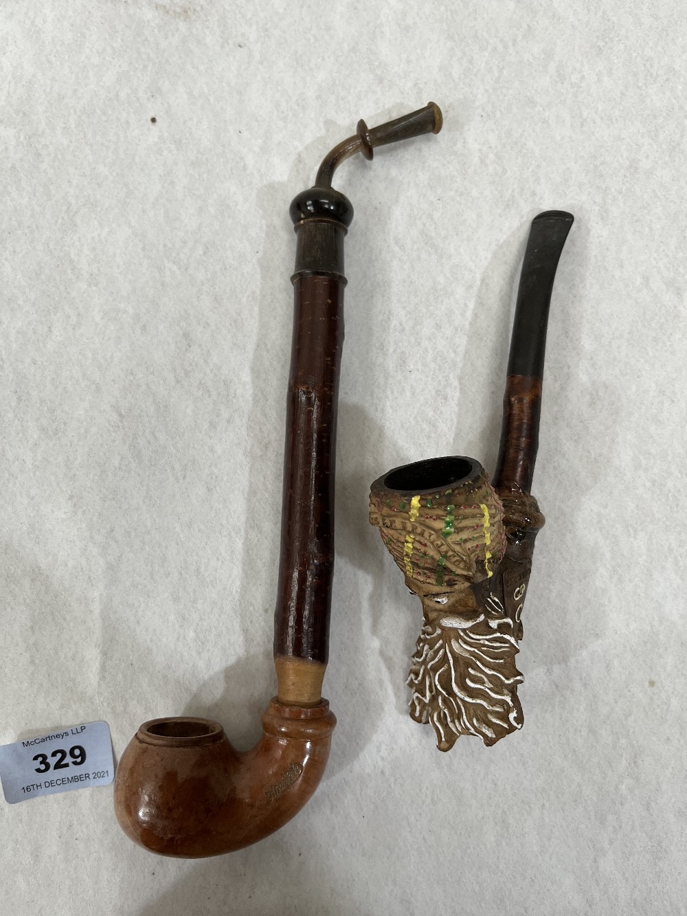 A continental briar pipe of bent form with naturalistic wood stem and horn mouthpiece 10' long;