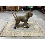 A 1950s push-along toy dog (re-covered) together with a rug