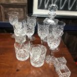 A CRYSTAL DECANTER WITH STOPPER AND CRYSTAL GLASSES AND NAPKIN RINGS