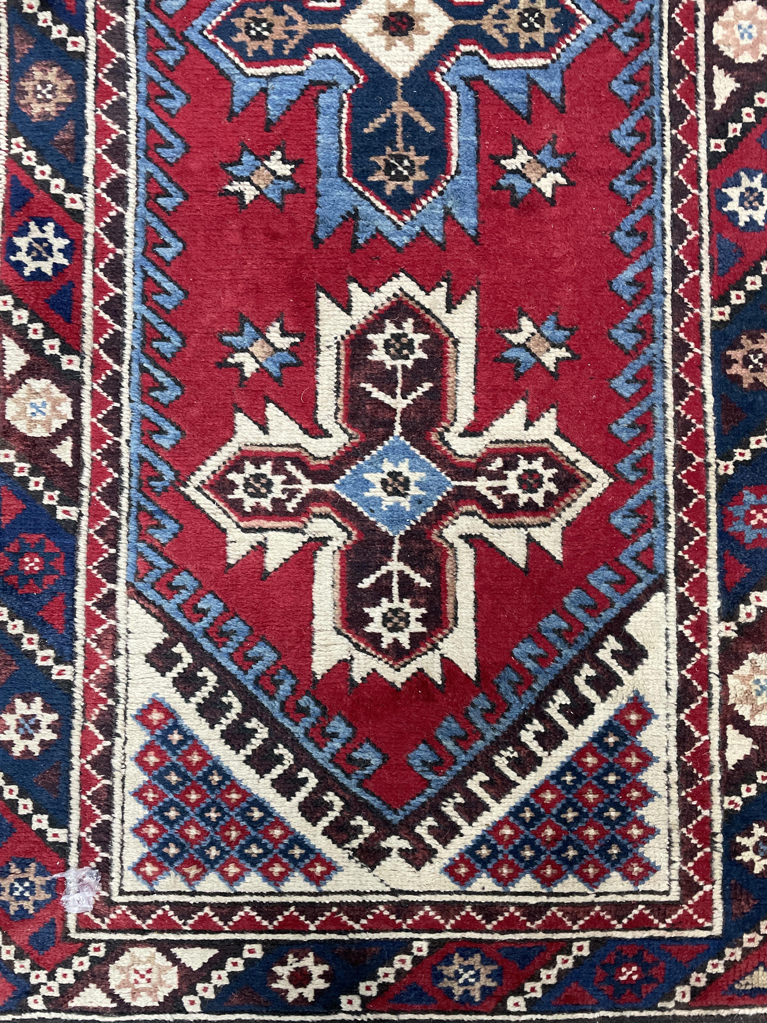 A MIDDLE EASTERN FRINGED AND BORDERED RUNNER AND A RUG