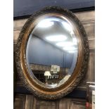 AN OVAL STAINED WOOD WALL MIRROR