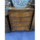 A REPRODUCTION SERPENTINE FRONTED CHEST OF DRAWERS