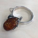 A CHARLES HORNER SILVER BANGLE AND A BALTIC AMBER PENDANT