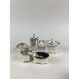 A SILVER THREE PIECE OVAL CRUETS SET AND TWO NAPKIN RINGS