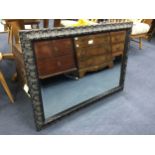 A MODERN RECTANGULAR WALL MIRROR IN AN EBONISED CARVED FRAME