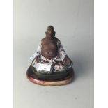 A CHINESE TERRACOTTA PART GLAZED SEATED BUDDHA