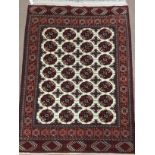 PERSIAN FRINGED RUG, decorated in shades of red with blue on a cream ground, 175cm x 120cm