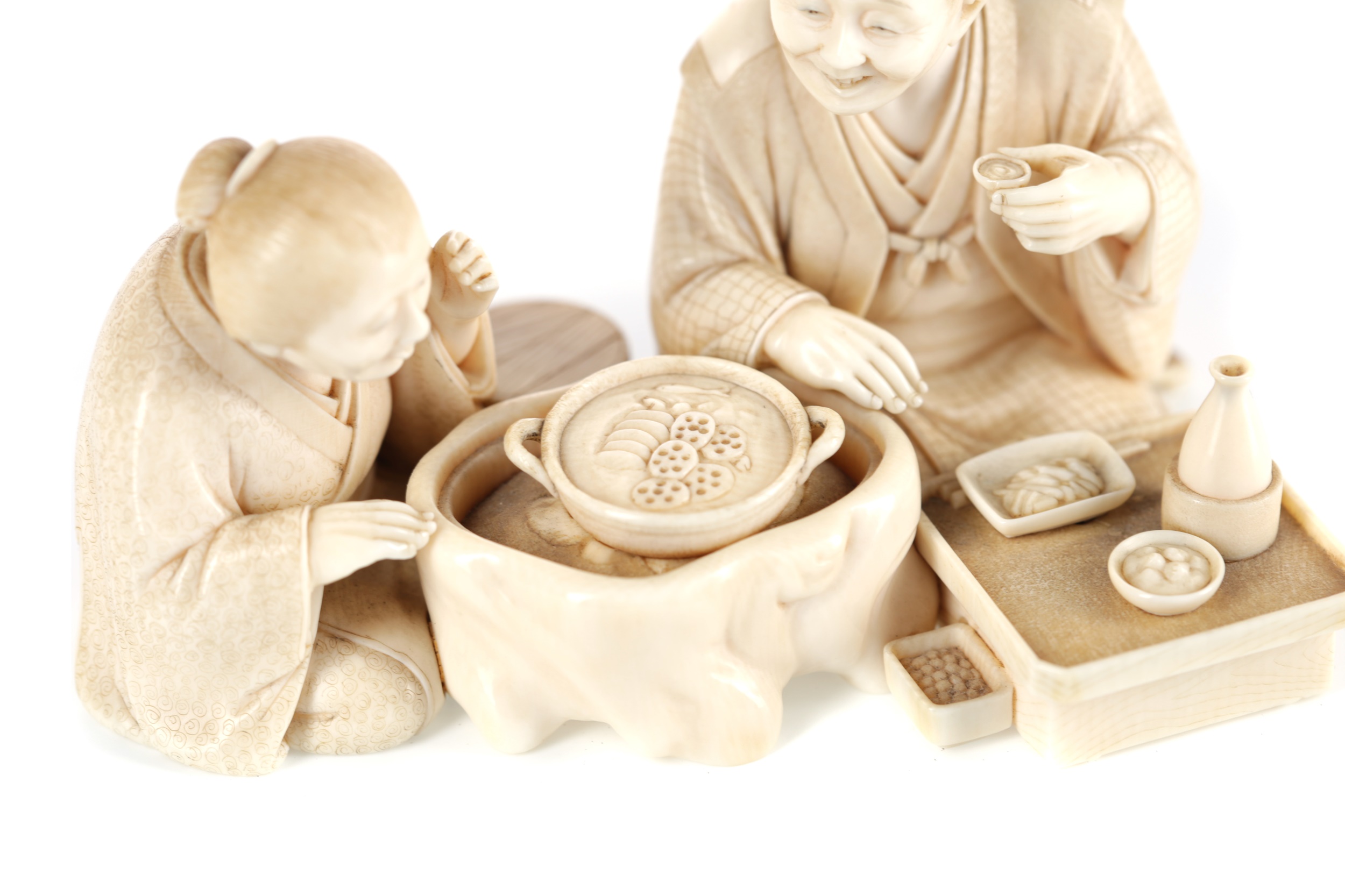 A FINE JAPANESE IVORY CARVING OF A SEATED GROUP, WITH GOLD SEAL MARK