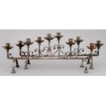A PAIR OF ARTS & CRAFTS EPNS CANDELABRA, C1930, OF FIVE LIGHTS LINKED BY C SCROLLS ON ARCHED LEGS,