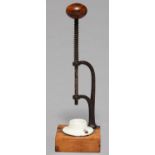 KITCHENALIA. A CHERRY-STONER, c1900,  OF STEEL WITH SPRING AND TREEN KNOB, WHITE EARTHENWARE