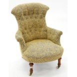A VICTORIAN WALNUT ARMCHAIR IN BUTTONED BLUE AND GOLD FABRIC, ON WHITE EARTHENWARE CASTORS, SEAT