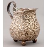 AN INDIAN SILVER REPOUSSE REAM JUG, KUTCH, LATE 198TH C, ON THREE BALL FEET, 86MM H, 3OZS 8DWTS
