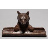 A SWISS BLACK FOREST CARVED LIMEWOOD BEAR NOVELTY INKWELL AND PEN TRAY, C1930, WITH BLACK BOOT