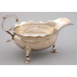 A GEORGE II SILVER SAUCE BOAT WITH FLYING SCROLL HANDLE ON THREE HOOF FEET, THE UNDERSIDE ENGRAVED