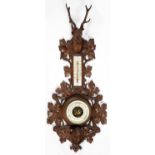 A SWISS CARVED LIMEWOOD ANEROID BAROMETER, EARLY 20TH C, WITH THERMOMETER, CARVED IN FULL RELIEF