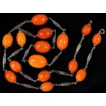 A NECKLACE OF FIFTEEN AMBER BEADS , C1920 WITH SILVER WIRE SPACERS, 81G Good condition; several