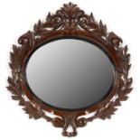 A CONTINENTAL CARVED AND STAINED  STAINED WOOD OVAL MIRROR, LATE 19TH C, THE UNBEVELLED OVAL PLATE