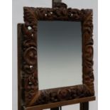 AN OAK CUSHION FRAMED MIRROR CARVED BY A BELGIAN PRISONER OF WAR, DATED 1915, 66 X 53.5CM, IN