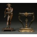 A FRENCH BRONZED SPELTER STATUETTE OF A CLOWN AND A PATINATED BRASS OIL LAMP BASE ON THREE SCROLLING