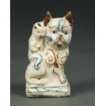 A TIN GLAZED EARTHENWARE FIGURE OF A CHINESE BOY SEATED ON A CAT, 19TH / 20TH C, PAINTED IN BLUE AND
