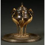 A  19TH CENTURY LIDDED INKWELL, THE CAPSTAN STYLE WELL SUPPORTED BY THREE GILTMETAL  STORKS, EACH