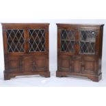 A PAIR OF REPRODUCTION GLAZED OAK CUPBOARDS WITH PAIR OF LEADED DOORS ABOVE PANELLED CUPBOARDS AND