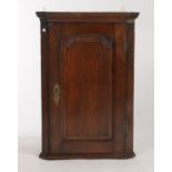 AN EARLY GEORGE III OAK HANGING CORNER CUPBOARD, C1760, WITH PLAIN CAVETTO CORNICE ABOVE A SINGLE