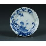 A CHINESE STYLE JAPANESE BLUE AND WHITE PLATE, 20TH C, PAINTED WITH NATURALISTIC PLANTS, 18CM